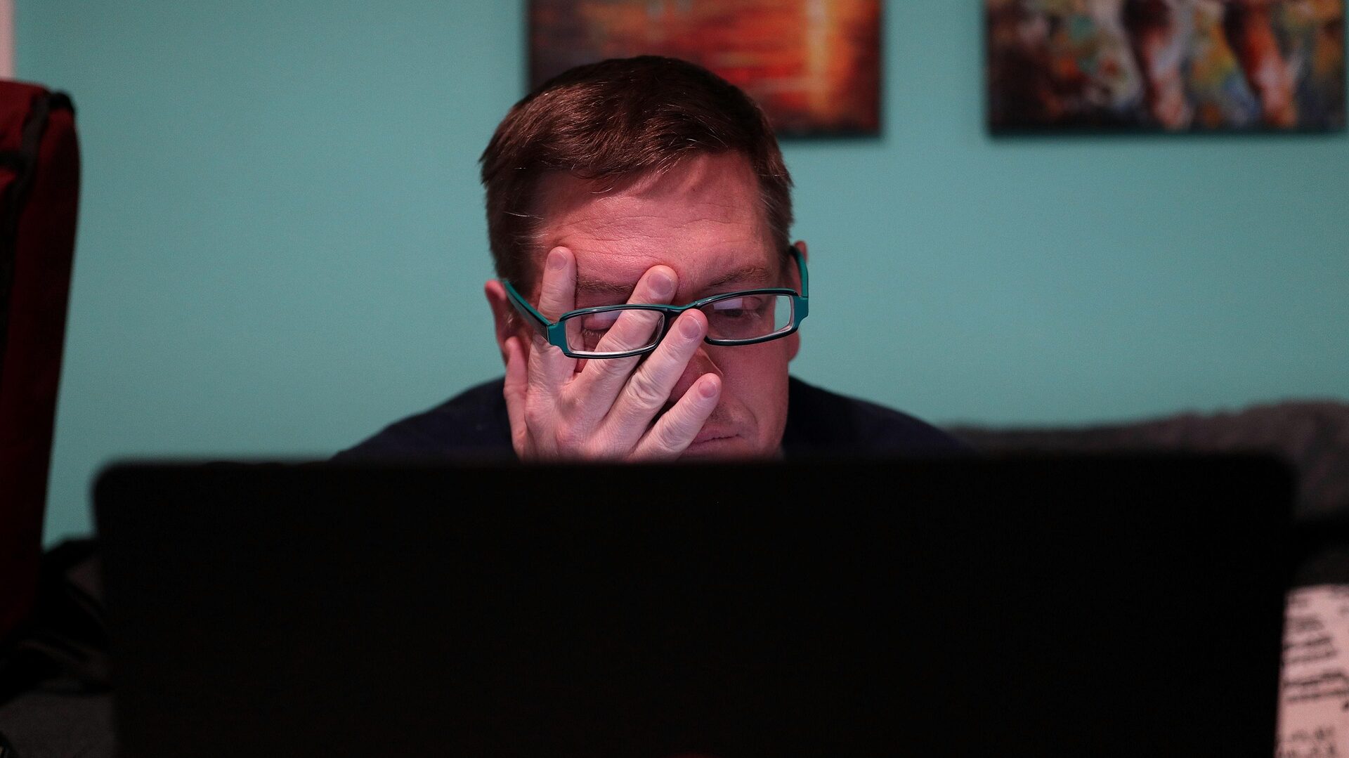 An exhausted man sitting in front of a monitor.
